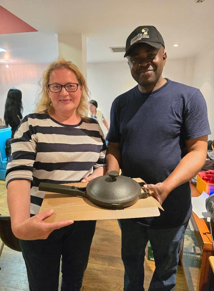 Two adults holding a wok at community event